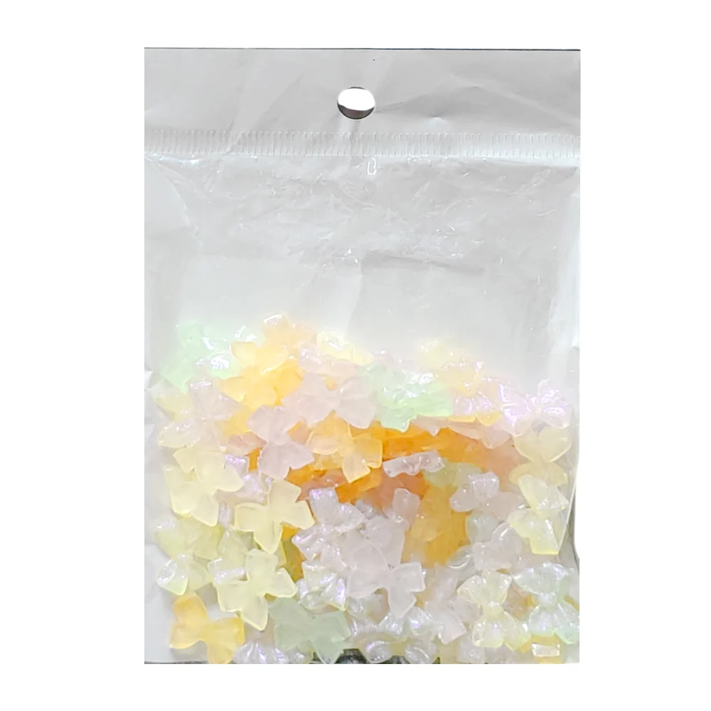 Paquete con 100 mini accesorios decorativos para uñas en forma de moño con efecto translúcido, variedad de colores / 210032